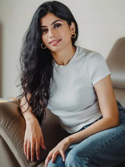 A warm and inviting portrait in a casual setting. The model's relaxed pose on a leather chair and her friendly smile create an approachable and genuine image.
