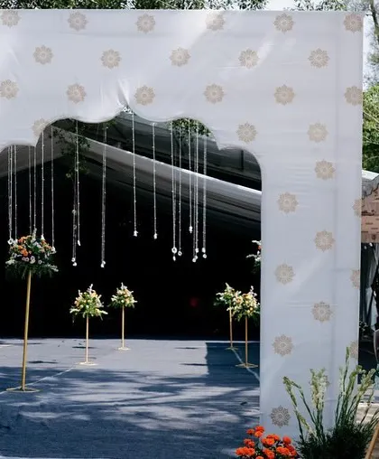 A welcoming archway for an outdoor wedding, designed with a custom print and delicate hanging flowers, setting the tone for a beautiful celebration.