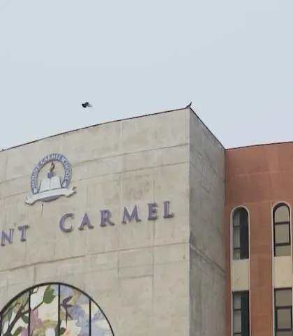 An exterior shot of the Mount Carmel building, showing the relationship between the concrete front, the red sandstone curved wall, and the pillared windows.