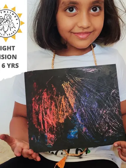 A proud child displays her 'Night Vision' scratch art. This is a classic and always magical activity where vibrant colors are revealed from beneath a layer of black.