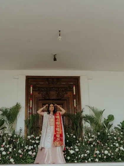 An elegant and simple stage setup for a Bhaat ceremony, with a backdrop of fresh flowers and greenery.