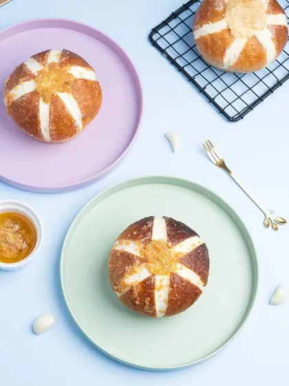 Korean cream cheese garlic buns arranged on pastel-colored plates. The top-down angle and soft colors create a trendy, aesthetic look for social media.