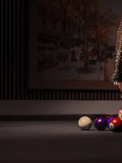A unique and modern bridal portrait, showing the bride in her full wedding attire, confidently posing at a pool table.