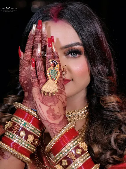 A playful and mysterious shot, with the model peeking through her henna-covered hands. This creative portrait highlights her beautiful eyes and festive makeup.