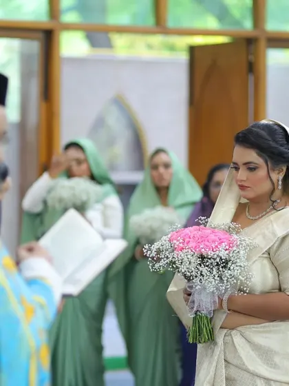 The bride listens intently during her Christian wedding ceremony, holding a beautiful bouquet of pink roses and baby's breath.