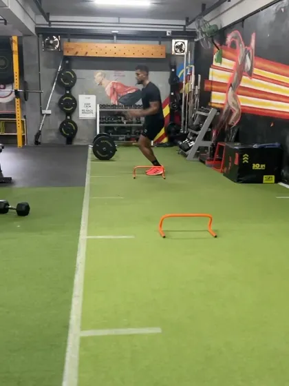 An athlete executes a lateral hurdle hop, a drill designed to improve side-to-side explosiveness and change-of-direction ability. This is crucial for sports that require multi-directional speed.