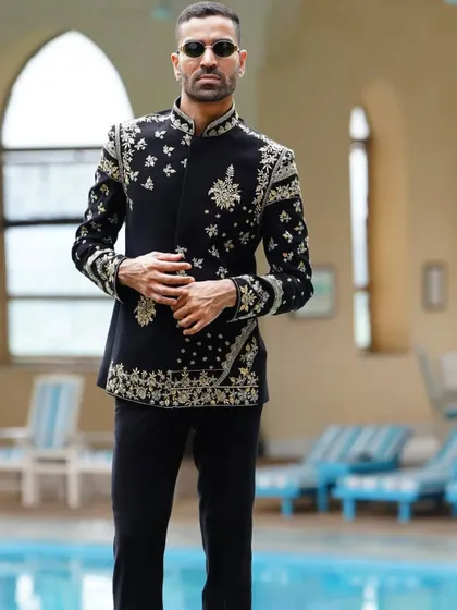 A black asymmetrical Jodhpuri jacket with scattered gold floral embroidery. The unique cut and placement of the motifs make this a high-fashion piece.