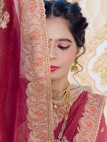 An artistic shot of a client in a maroon saree, with half her face covered by the veil.