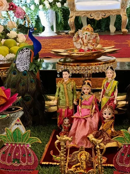 An elegant seemantham decor featuring peacock feathers, decorated kalashas, and a family of dolls, creating a complete traditional scene.