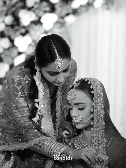 A sister's love. A black and white shot of a tender moment between the bride and her sister during the ceremony, a quiet exchange of support and affection.
