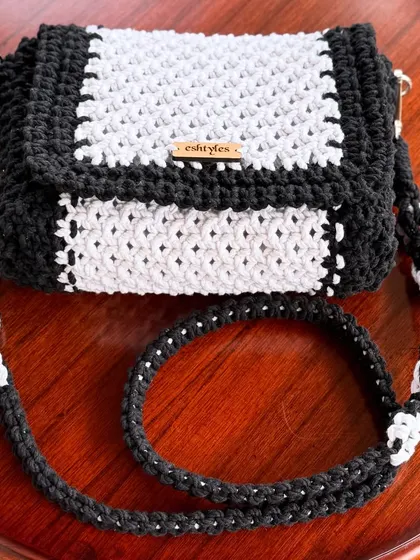 A top-down view of the black and white sling, showing the strap and the neat knotting.