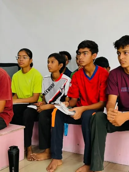 Young athletes listen intently during a mindset training class. We believe in building smart fighters who understand the 'why' behind their training, not just the 'how'.
