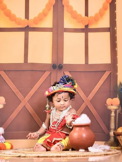 This rustic setting with a wooden door backdrop gives a traditional village feel to our Baby Krishna photoshoot. Every prop is carefully chosen to build a complete, story-rich environment.