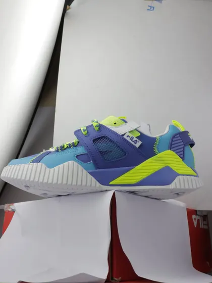 The raw behind the scenes shot of a colorful Fila sneaker, showing how it was propped up on a box for the photo.