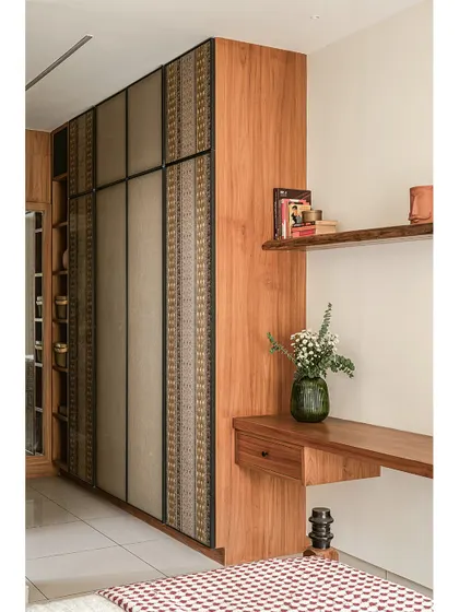 In the 'Kayu' bedroom, I used fabric-lined wardrobe shutters to complement the natural teak wood. This detail adds a layer of texture and softness to the room, blending storage seamlessly into the overall design.