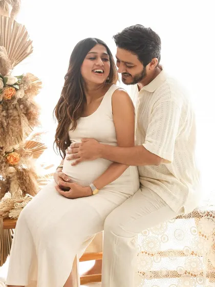 A playful and loving interaction during a boho-themed maternity shoot. The earthy tones and textures of the studio setup complement the couple's relaxed and happy vibe.
