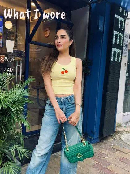 All I do is dress up and have coffee. A cute outfit featuring a yellow cherry-print top and jeans, outside a cafe in Delhi.