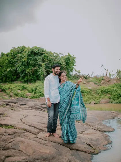 A candid shot of a couple enjoying the view from a rocky outcrop by the water.