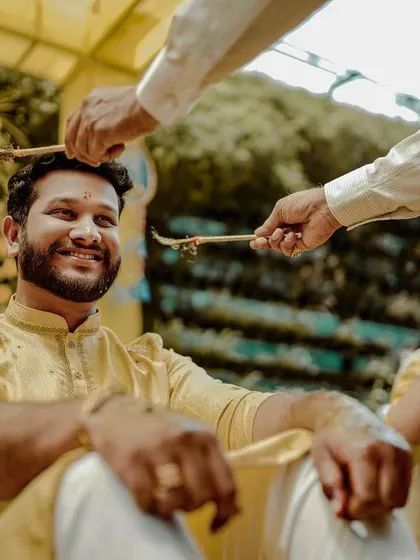 The groom smiles as turmeric paste is applied during a traditional Haldi ritual.