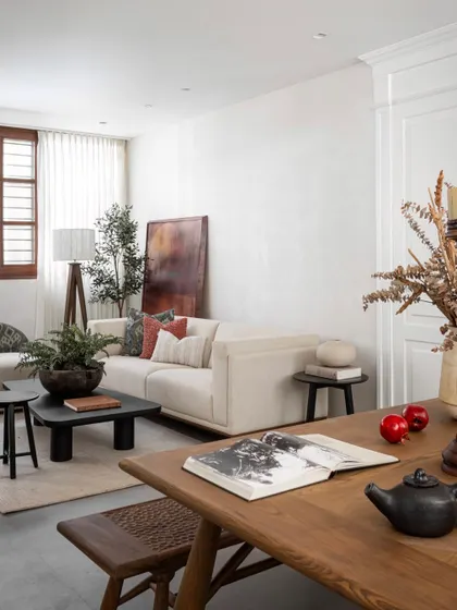 This angle shows the living area with its low-slung sofa, layered cushions, and a casually leaning piece of art. The space feels relaxed, with every element chosen for its sculptural and textural quality.