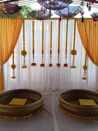 A closer look at the main seating area for the Haldi, with two large brass urlis and a clean white and yellow backdrop.