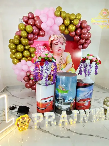 A fun combination theme featuring Disney's Cars characters on the plinths and a backdrop of the birthday boy dressed as Krishna.