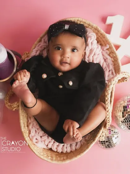 An overhead shot of one of the twin girls in a basket, surrounded by disco balls and party props for their half-birthday.