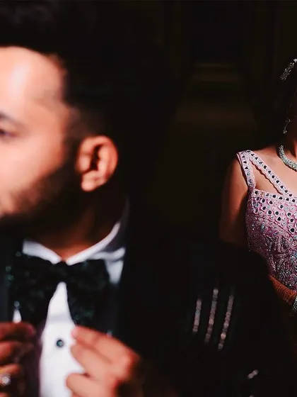 A classic portrait from an engagement ceremony. The groom is in sharp focus while his bride looks on from the background, creating a sense of depth and storytelling in a single, elegant shot.