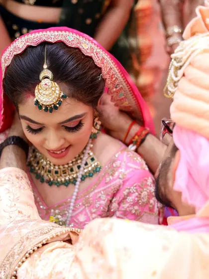 A beautiful moment between the bride and groom. Her pink lehenga is paired with soft, romantic makeup, including a touch of pink on the eyes.