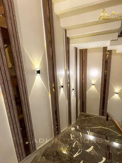 Another view of the staircase, showing how the combination of dark marble steps, glass railing, and strategically placed wall lights creates a dramatic and stylish effect.