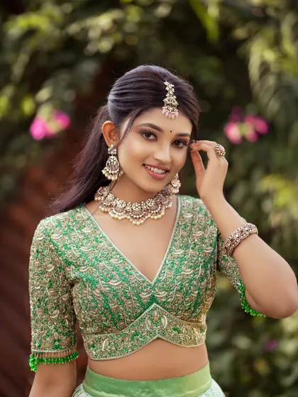 The smile says it all. This close-up showcases the beautiful fit and flattering V-neckline of the embroidered blouse, paired with delicate pearl jewelry to complement the green half saree.