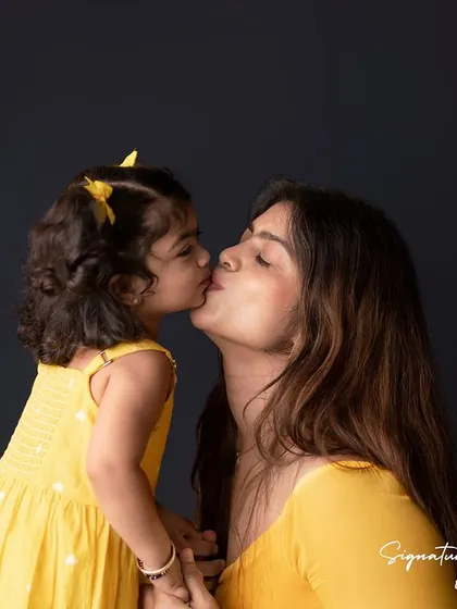A sweet kiss between mother and daughter. This intimate and tender moment is what makes these "Mom & Me" sessions so special, creating a timeless portrait of their bond.