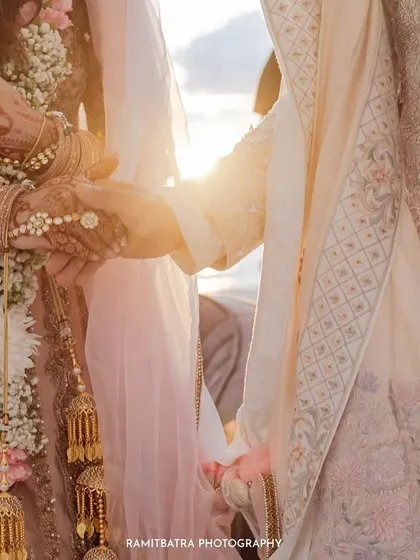 A close-up shot of the couple's hands during the ceremony, with the setting sun creating a beautiful flare.