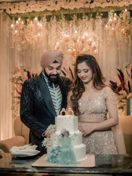 The sweet beginning. Simran and Sanjit share a smile as they prepare to cut their beautiful, multi-tiered engagement cake, surrounded by opulent decor.