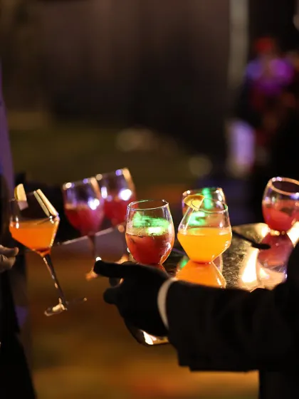 A tray of assorted colourful mocktails is carried by a server. This demonstrates our "moving starters" concept applied to drinks, ensuring guests always have a refreshing beverage in hand.