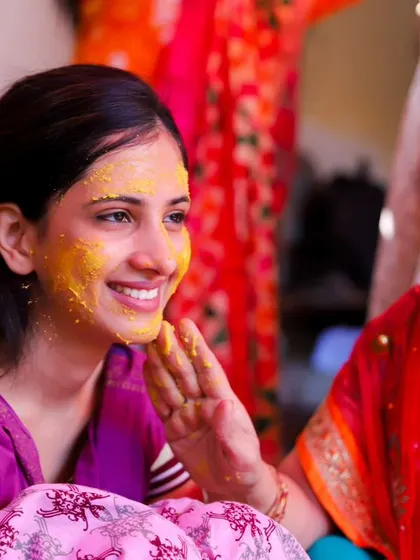 A gentle moment between mother and daughter. A mother lovingly applies turmeric to her daughter's face during the Haldi ceremony, a classic and emotional ritual.