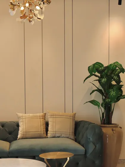 Detail shot of a modern living area, focusing on the material palette. A plush sofa, a statement plant in a ceramic pot, and a striking floral-inspired chandelier come together to create a corner that feels both luxurious and gracefully simple.