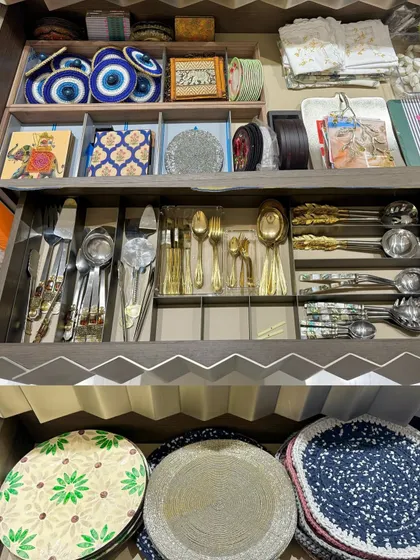 A unique drawer with custom zig-zag detailing, organized with fine cutlery, placemats, and decorative items. This shows our ability to work with any style of cabinetry.
