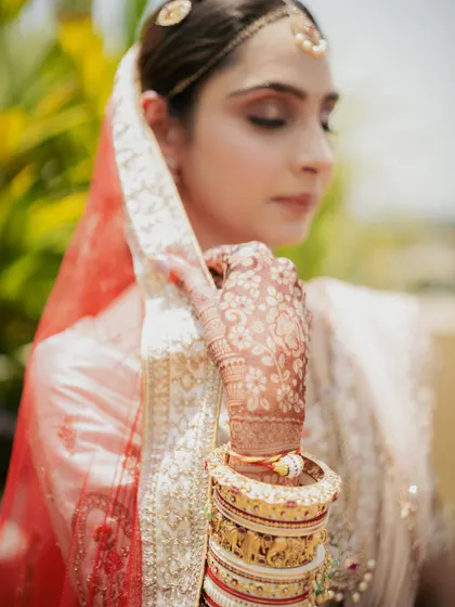 A close-up on the bride's hand, showcasing her beautiful bridal bangles and the delicate mehndi design.