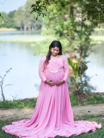 A serene portrait of a mom-to-be in a pink gown by a lake.