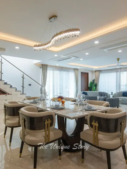 A wide-angle shot showing the open-plan layout connecting the living and dining areas. The consistent marble flooring and sophisticated lighting scheme create a cohesive and expansive feel throughout the ground floor.