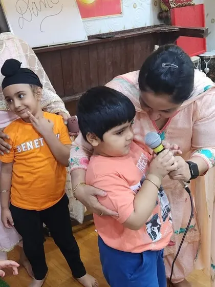 Our teachers ensure even the youngest participants get a chance to shine. Here, a child is helped with the microphone, fostering a sense of inclusion and building social skills from an early age.