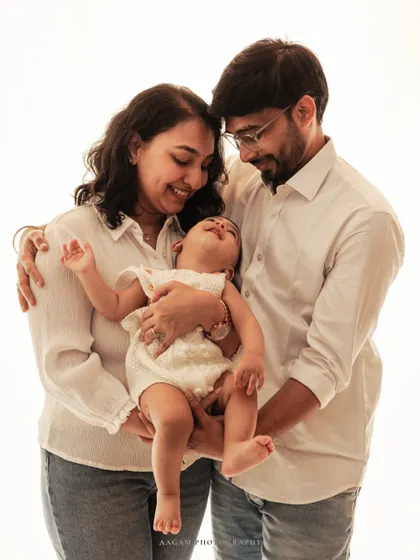A moment of pure bliss. A baby laughs with delight while being held by loving parents in this beautiful high-key family portrait.