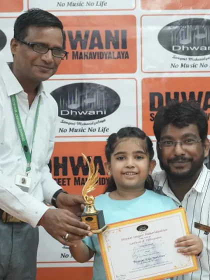 A teacher presents an award to a very young and happy student.