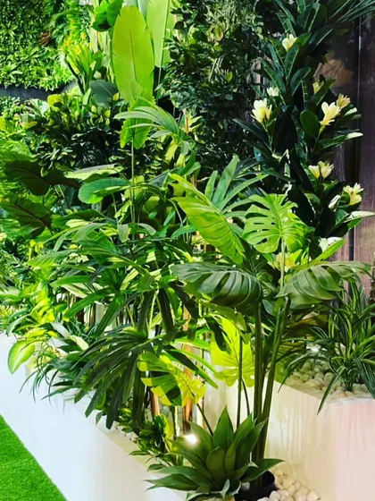 This is a planter box filled with a variety of lush, tropical artificial plants like monsteras and palms. It acts as a beautiful and maintenance-free divider in a commercial space.