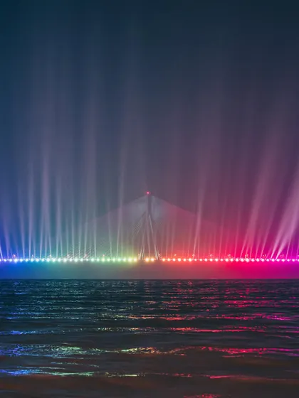 A stunning long-exposure shot of the Bandra-Worli Sea Link illuminated with colorful lights at night. This captures a magical and rarely seen view of the iconic bridge.