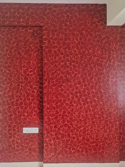 A high-impact accent wall featuring a rich, deep red textured paint finish. The intricate, sponge-effect pattern adds depth and a dramatic touch to the space.