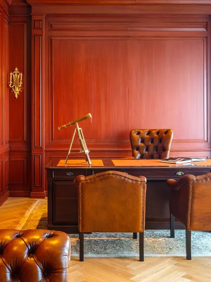 The director's desk at Paras Buildtech is set against a backdrop of rich, red-toned wood paneling. The space is designed to feel classic and powerful, reflecting the client's dedication to quality and excellence.