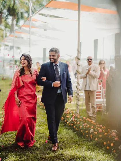A happy couple walks down the aisle after their ceremony, surrounded by the beauty of a garden in full bloom.