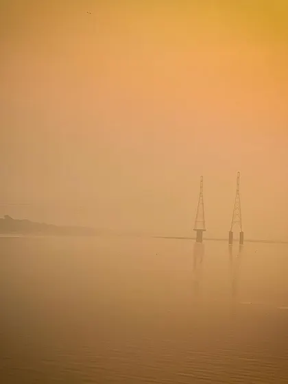 Two towers stand like lonely sentinels in the water, shrouded in a thick, golden morning mist. This image has a very painterly and almost surreal quality.